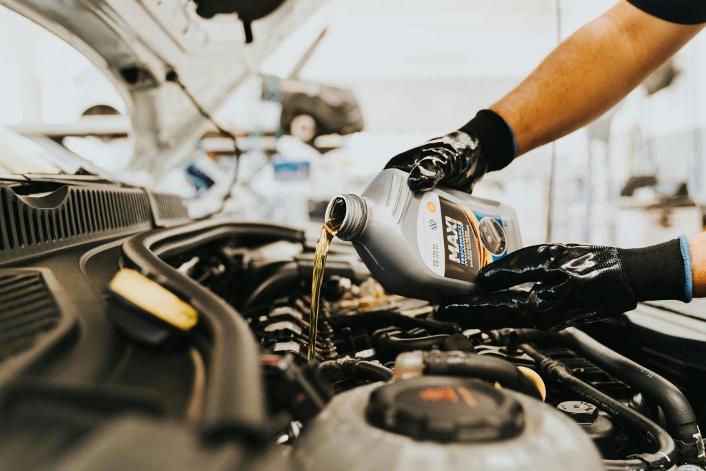 pexels photo 13065690 13065690 Close-up of a mechanic pouring engine oil into a car engine in an auto repair shop.